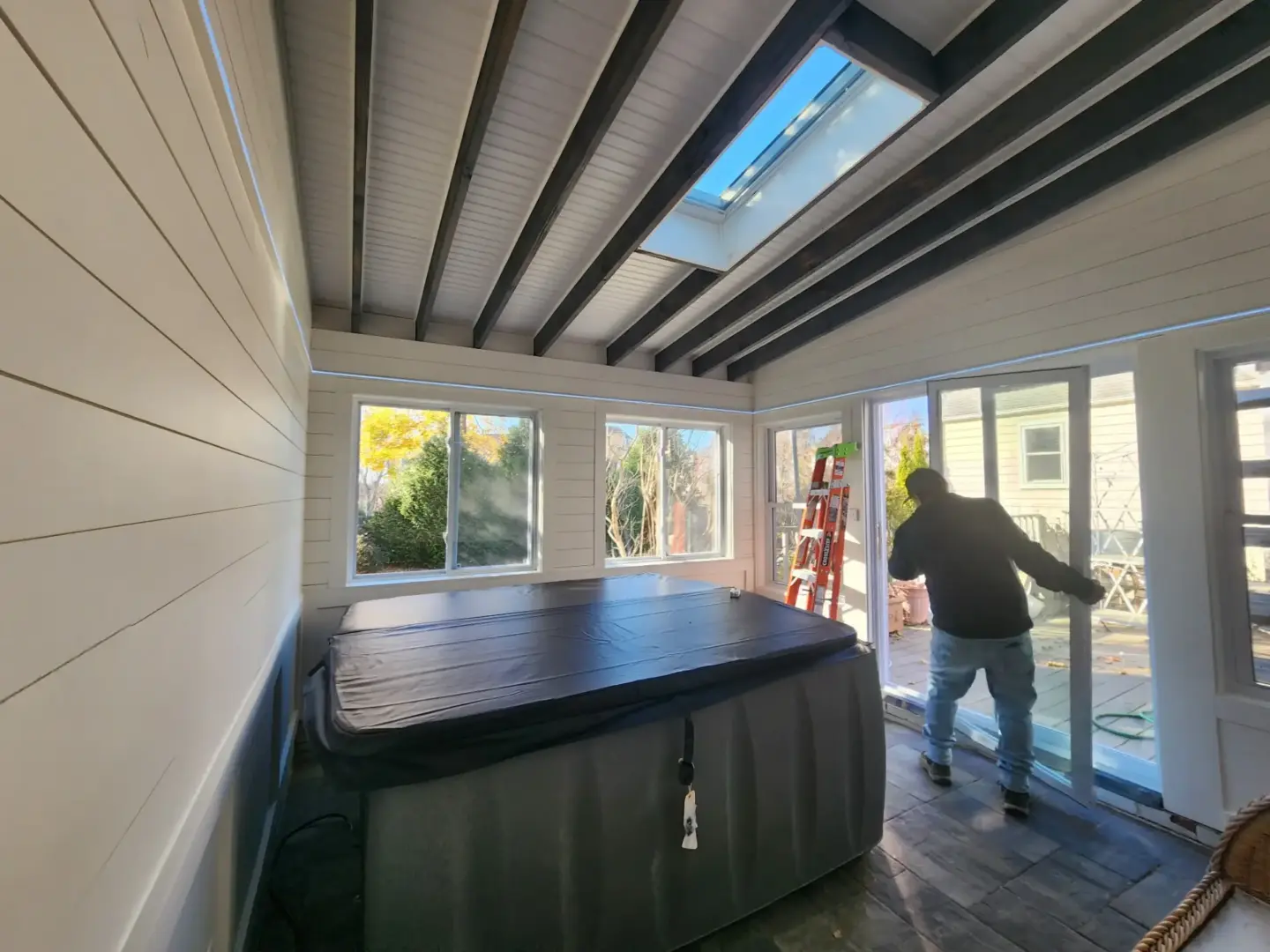Sunroom with hot tub skylight windows and person opening sliding door